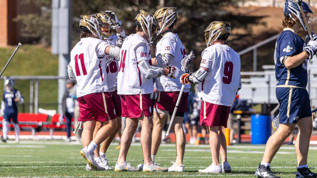 Bridgewater College lacrosse players huddle together on the field