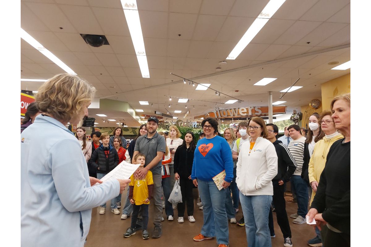 Several participants stand in a group to hear instructions and rules for the event.