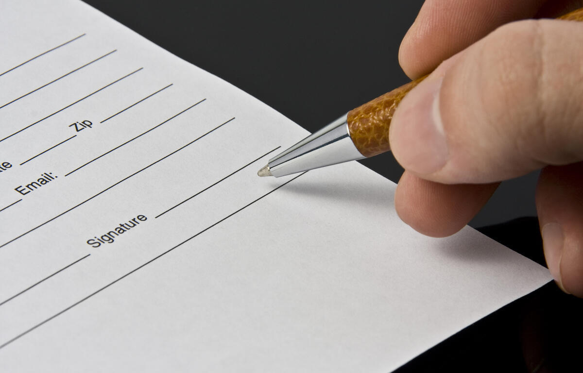 Man's hand signing the document
