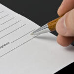 Man's hand signing the document