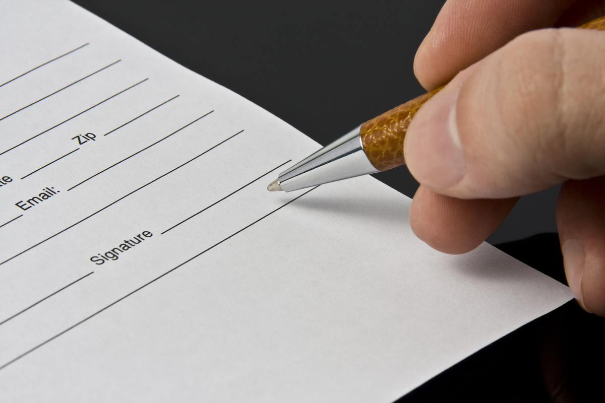 Man's hand signing the document