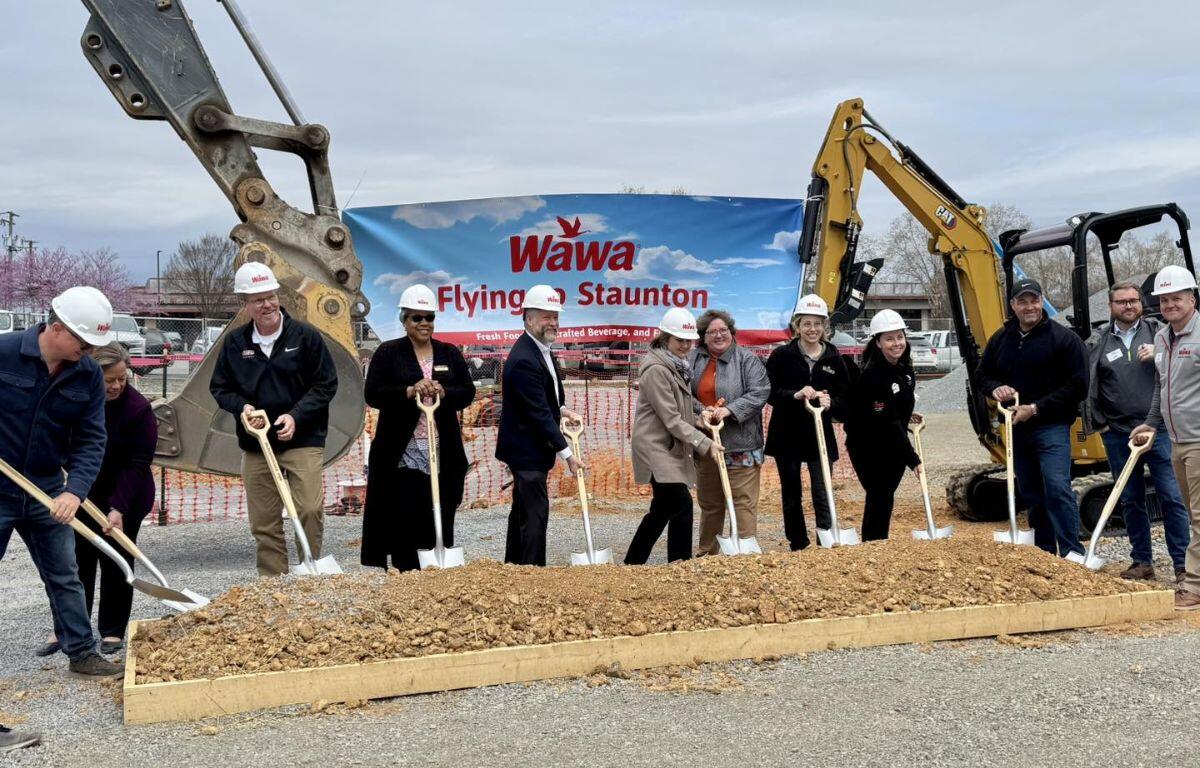 Members standing in front of equipment with shovels