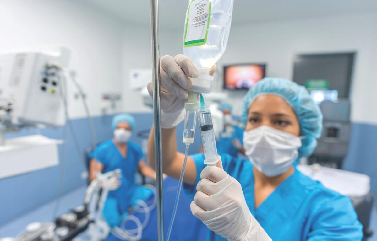 Doctors check an IV bag.