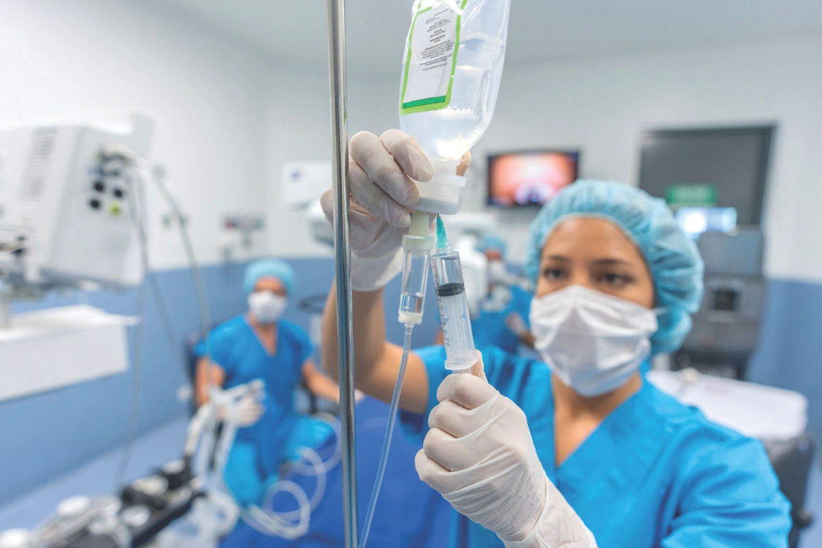 Doctors check an IV bag.