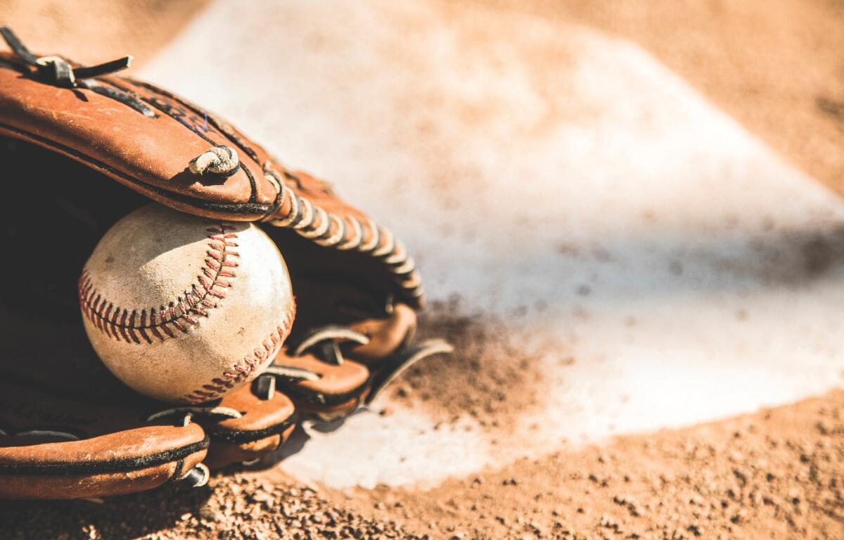 Baseball glove holding a baseball on homeplate.