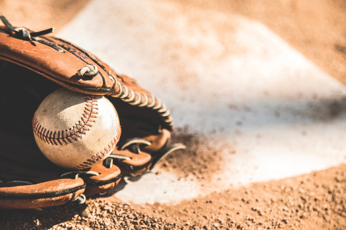 Baseball glove holding a baseball on homeplate.