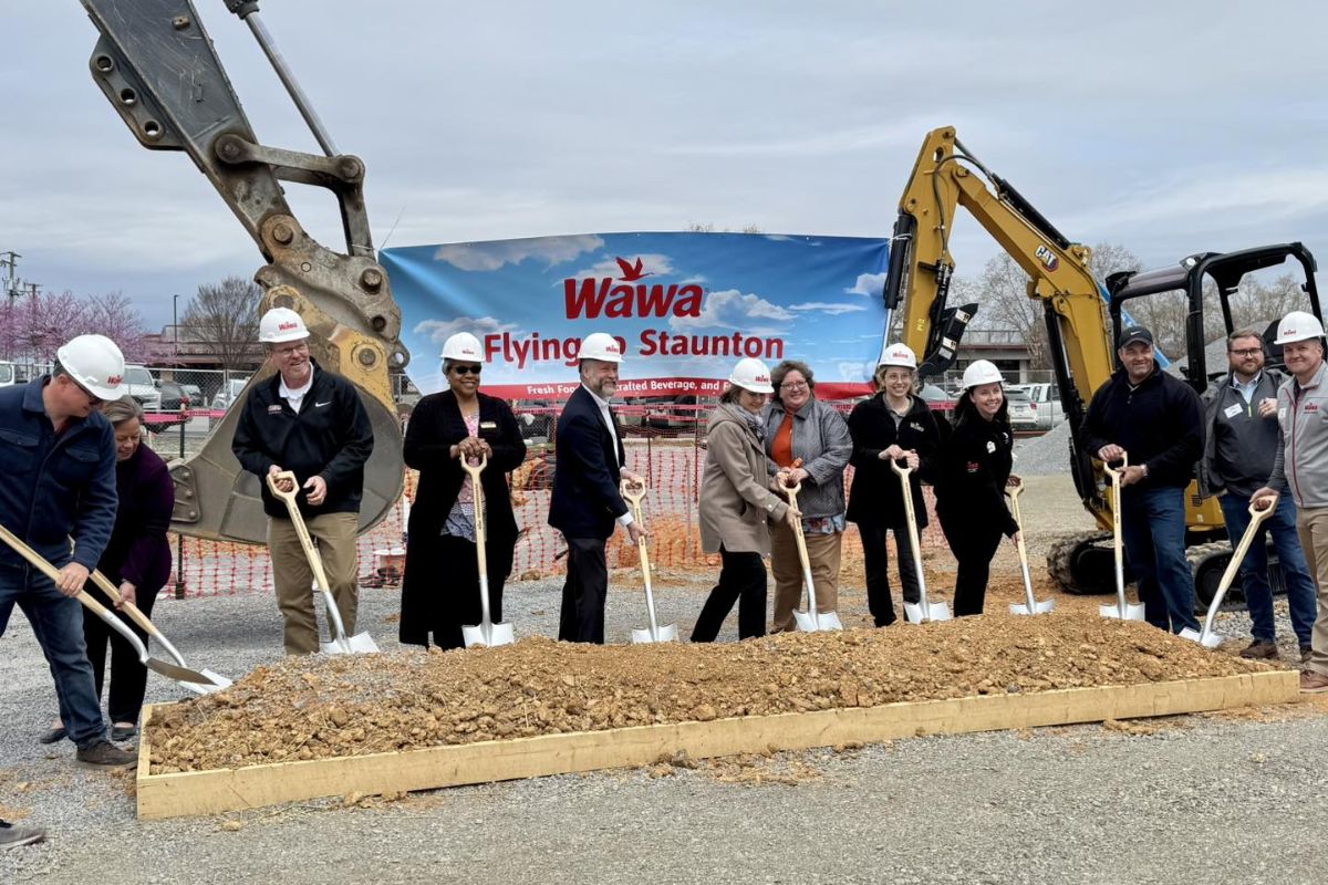 Members standing in front of equipment with shovels