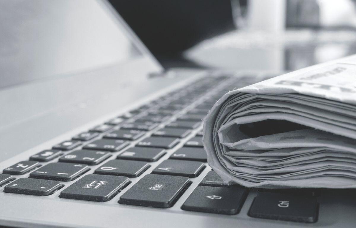 Laptop with rolled up newspaper on top of keyboard