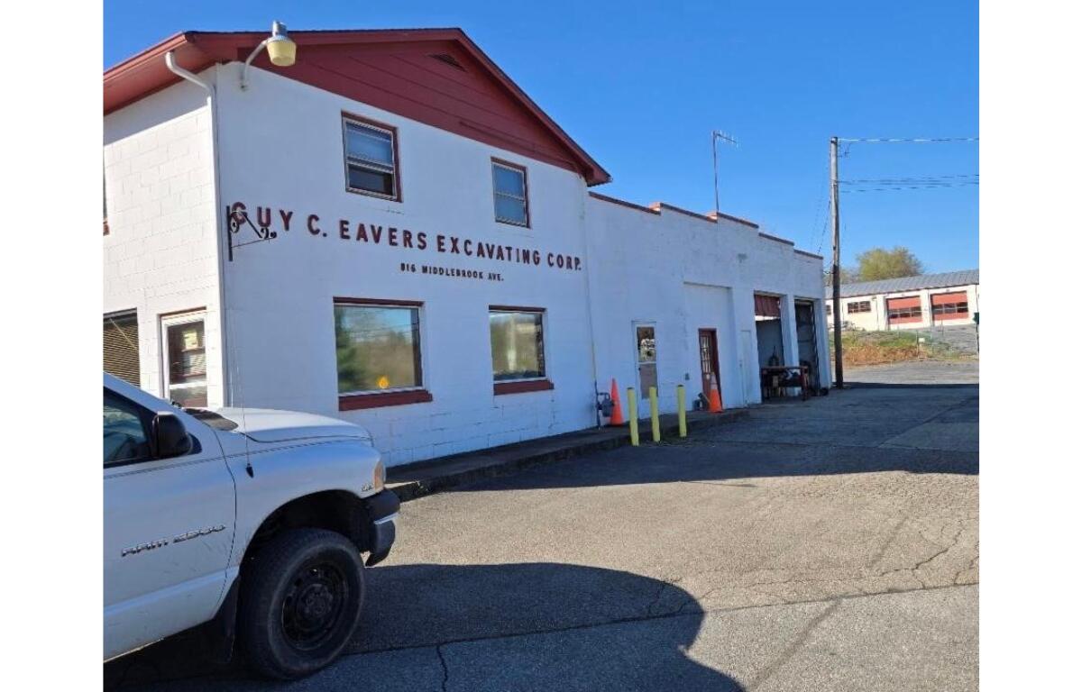 A photo looking at the outside of the Eavers Property. A white building with a red roof.