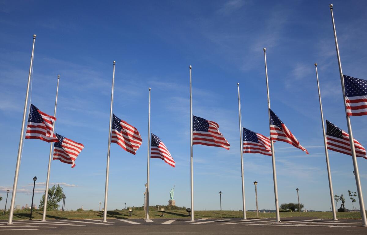 Multiple flags flying half-staff on flag poles.