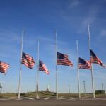 Multiple flags flying half-staff on flag poles.