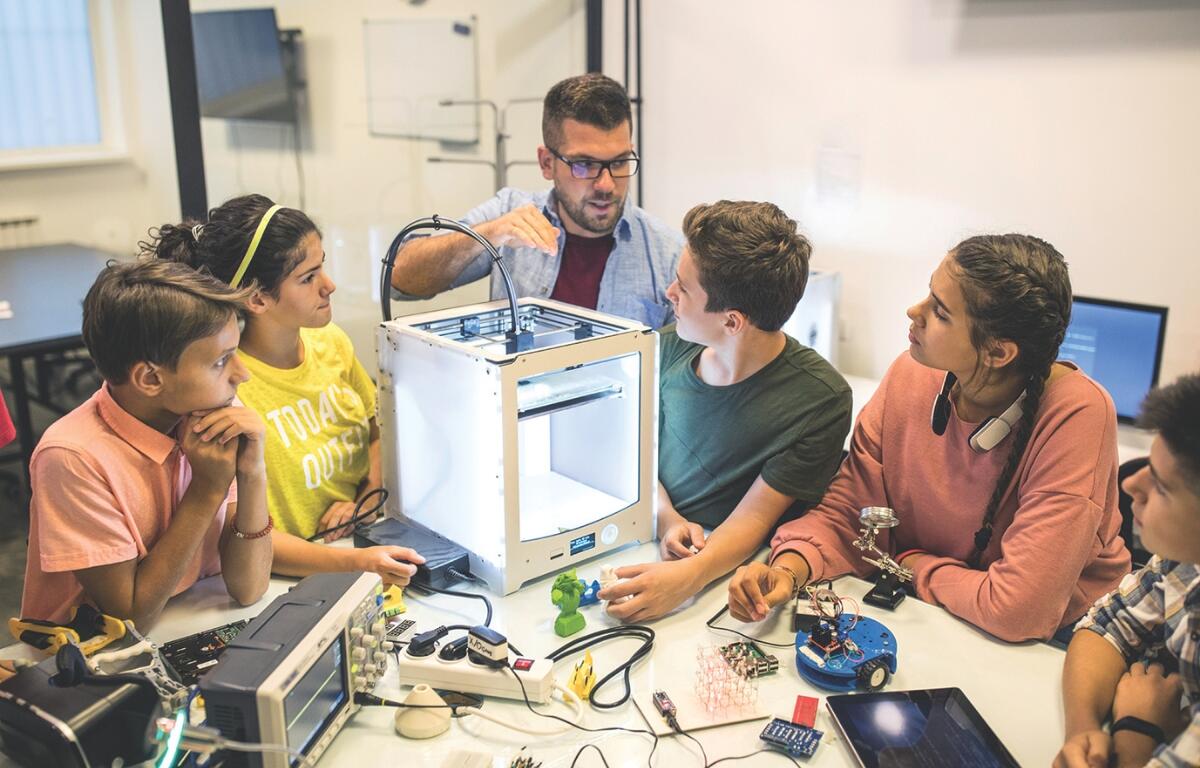 Students learning from a teacher about computers.