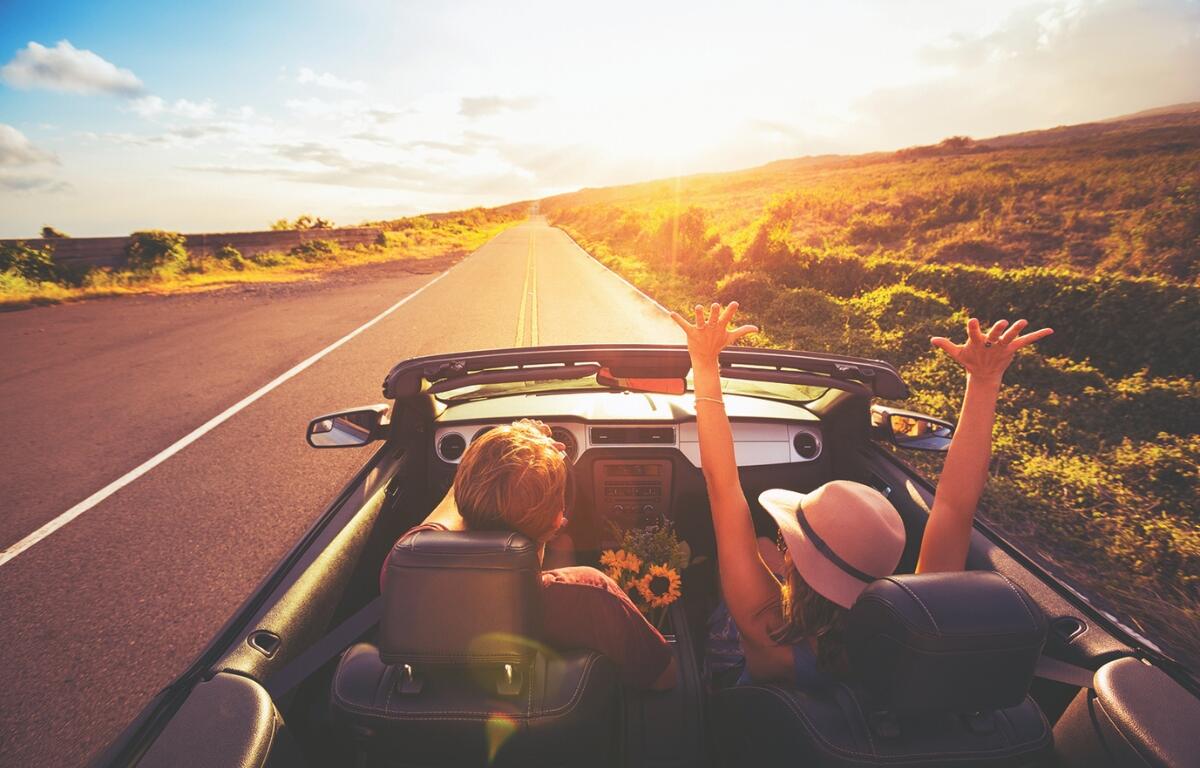 Car driving down the open highway at sunset.