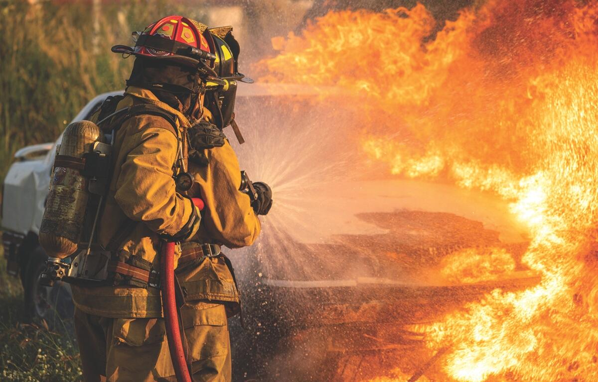 Two firefighters put out a car fire.