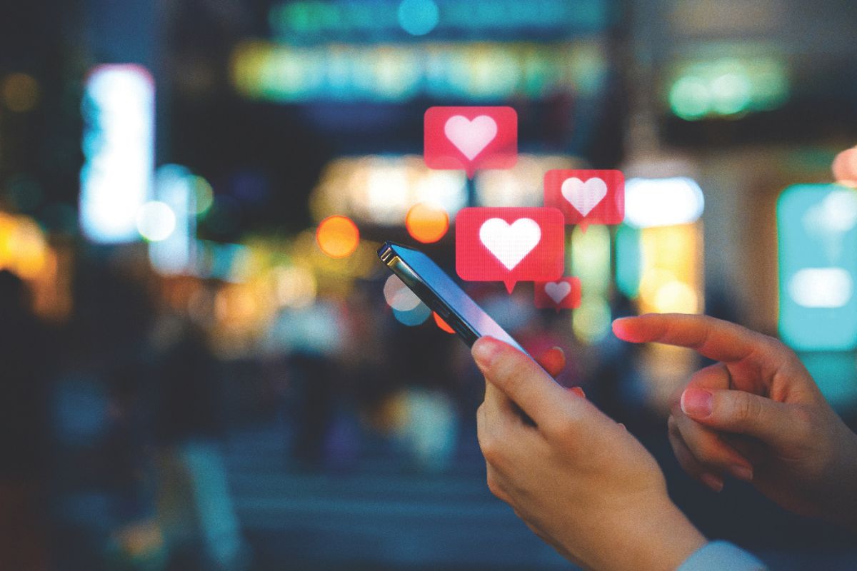 A person holding a phone and heart graphics above the cellphone