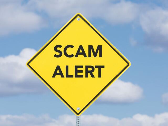 Scam Alert on yellow sign with clouds in the background