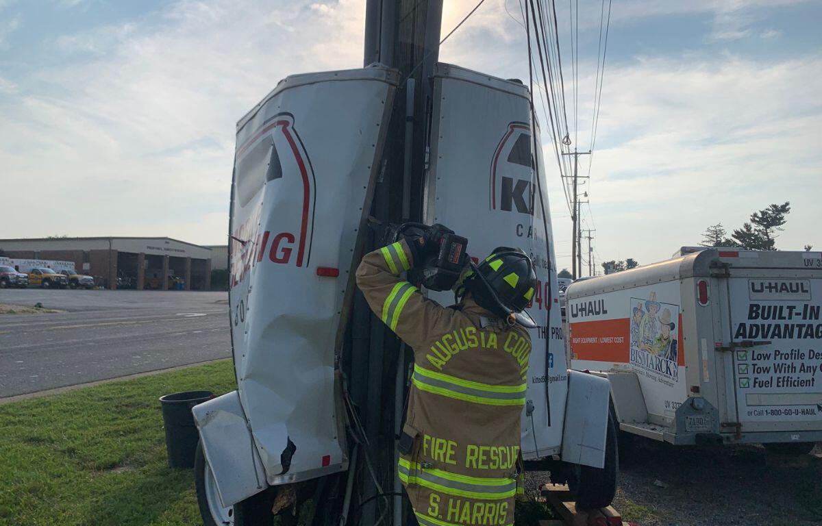 Firefighter dislodging trailer around utility pole