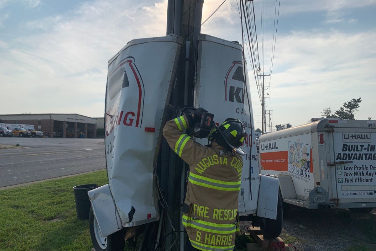 Firefighter dislodging trailer around utility pole