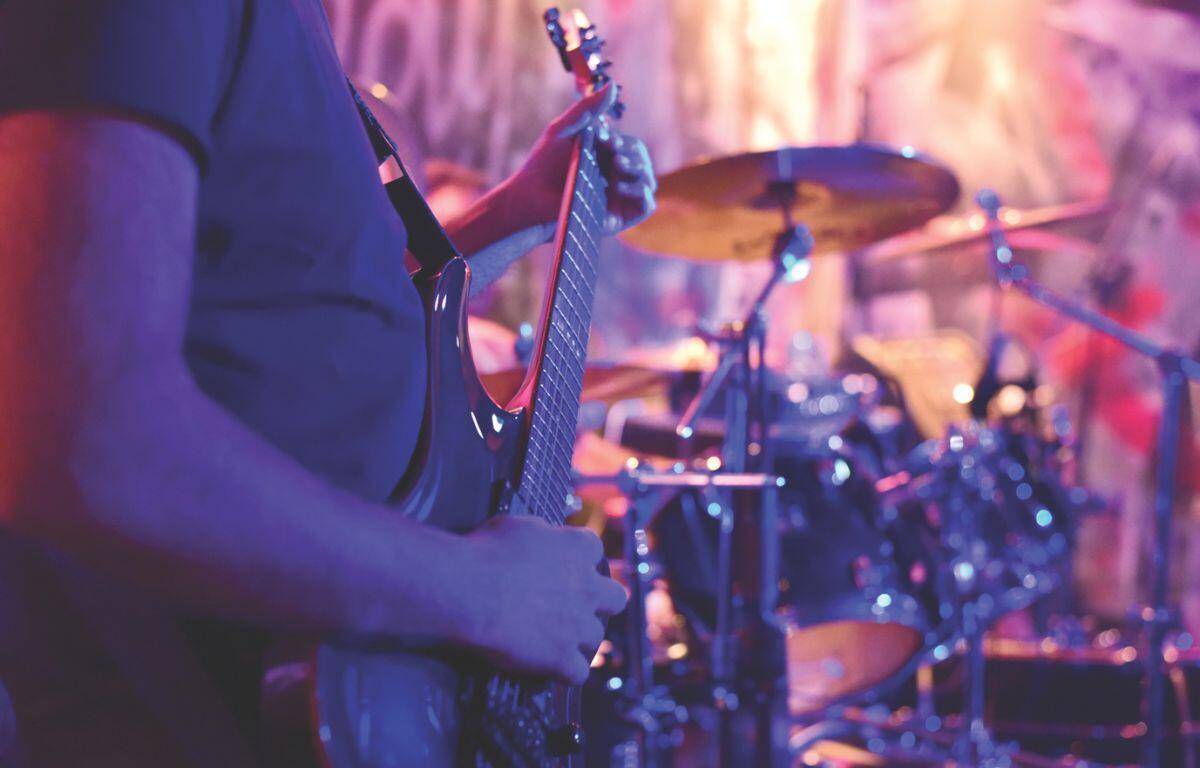 guitar player playing in front of drums