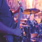 guitar player playing in front of drums