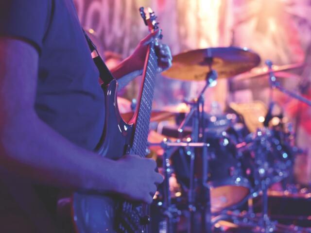 guitar player playing in front of drums