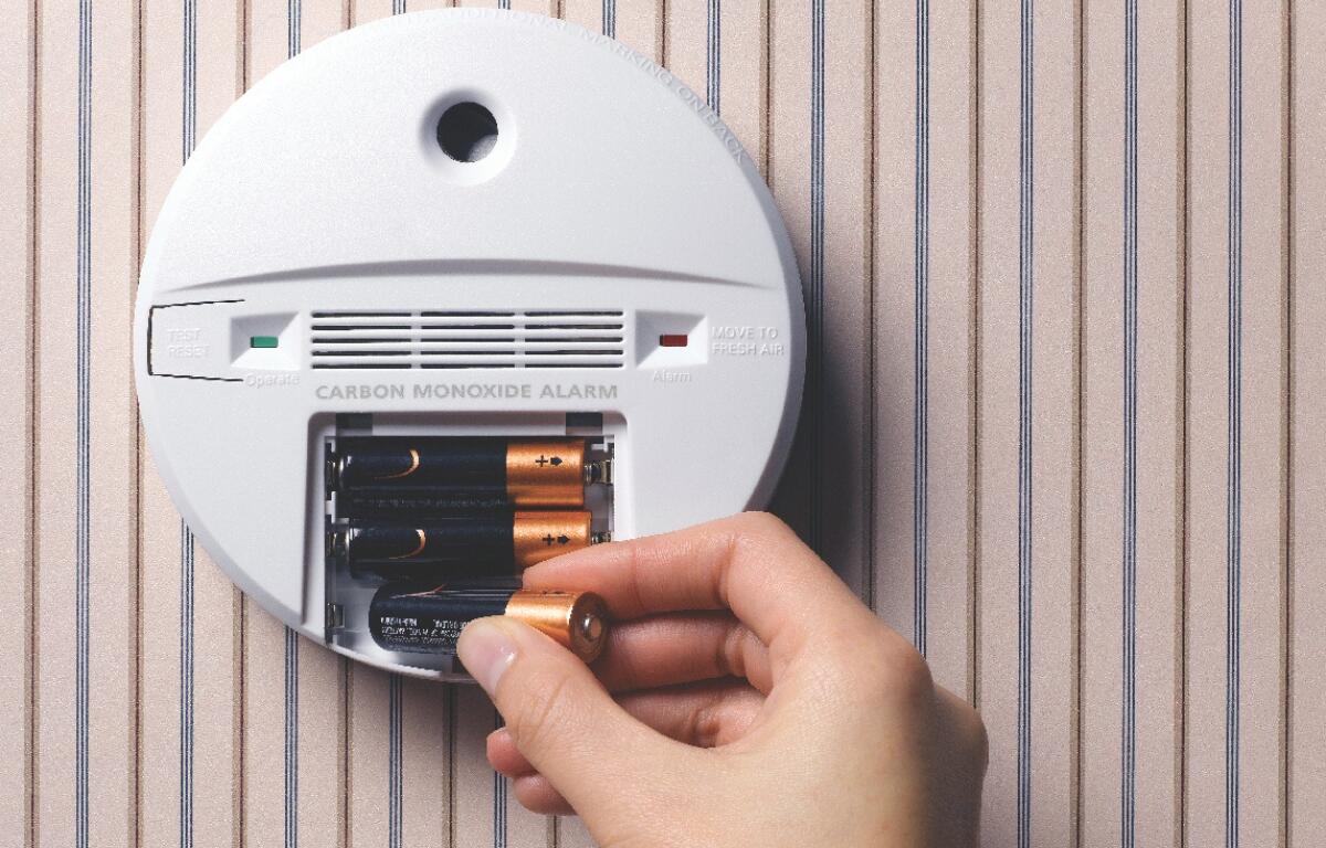 A person changing the batteries in a smoke detector.