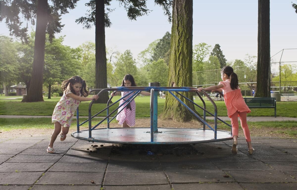 Three girls spinning on a merry go round.