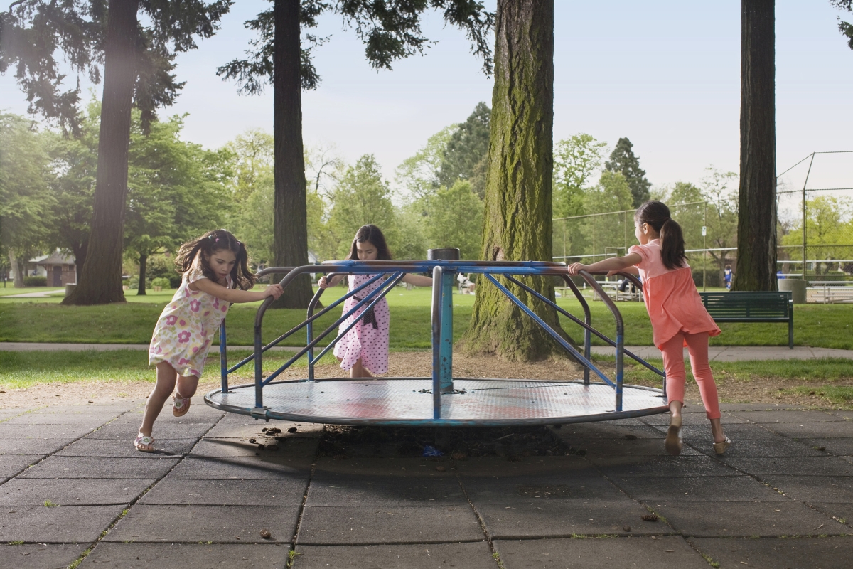 Three girls spinning on a merry go round.