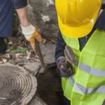 Two workers going into a manhole.