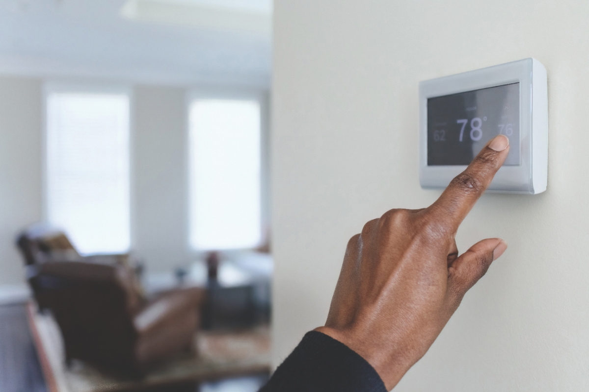 Someone turning down a thermostat on a wall.