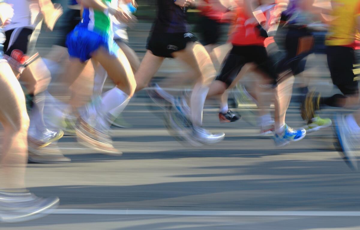 Multiple people running on pavement in a marathon.