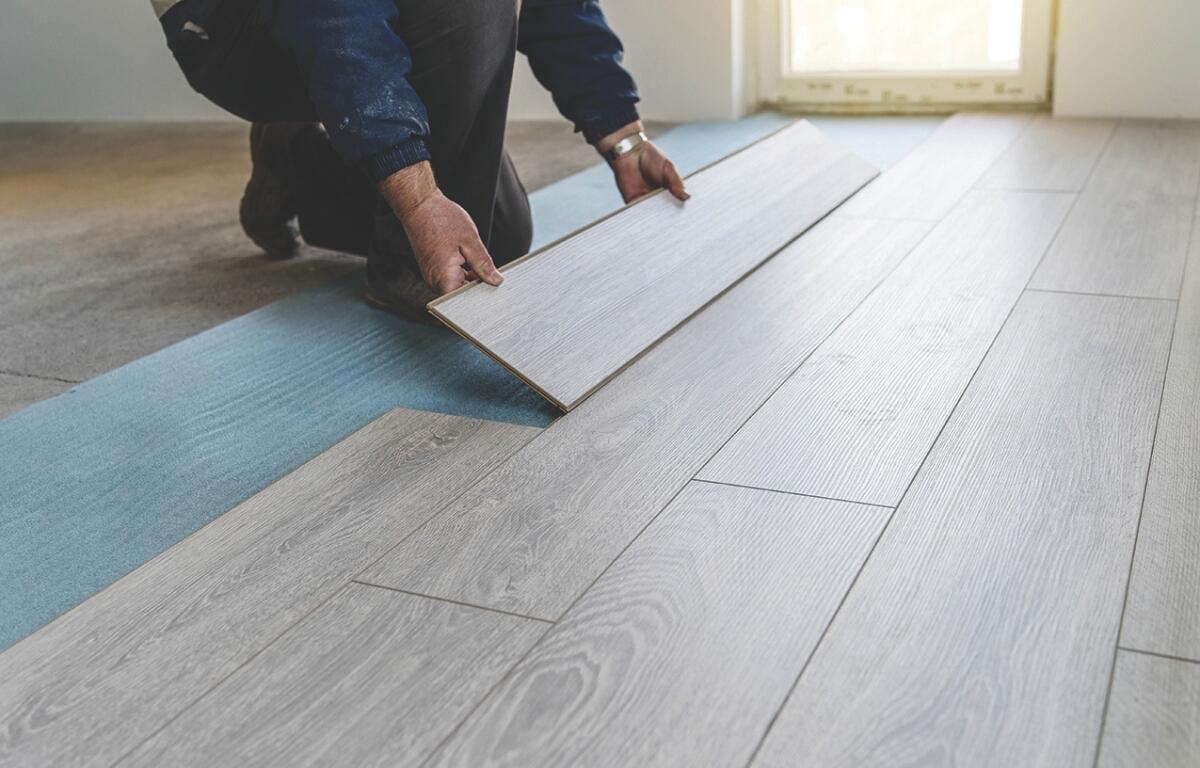 A person laying hardwood flooring.