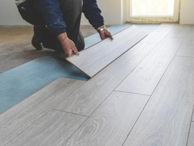 A person laying hardwood flooring.