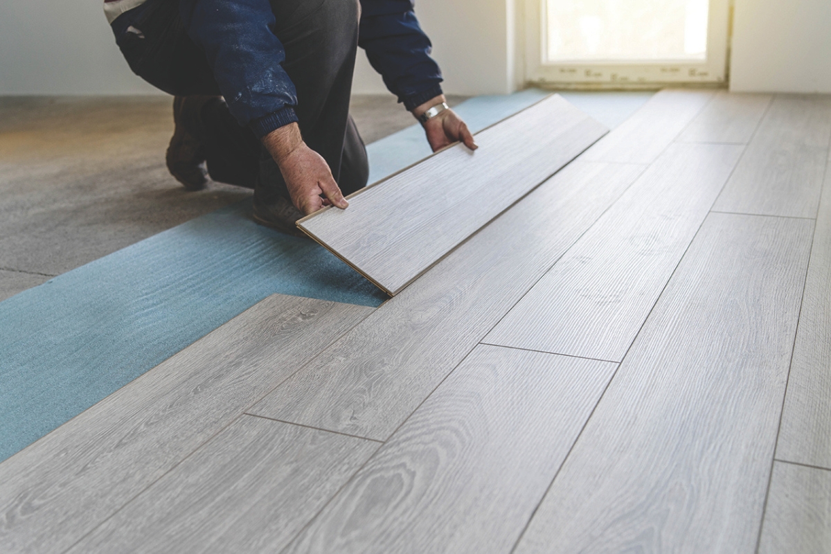 A person laying hardwood flooring.
