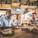 A group of people eating and laughing around a table in a restaurant.