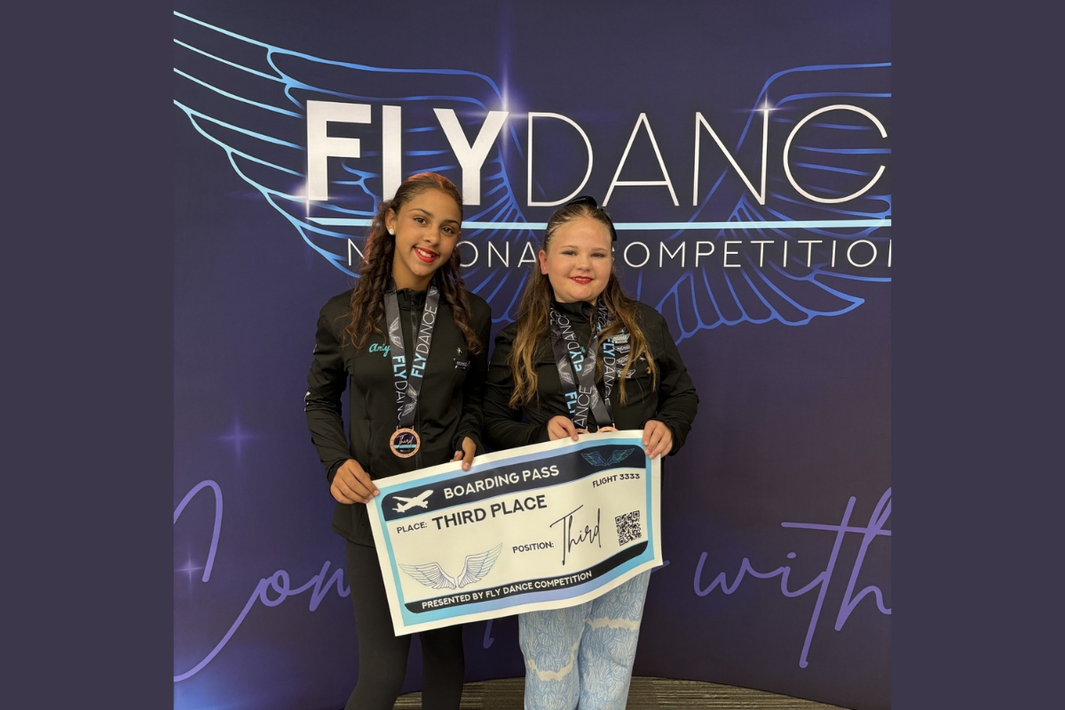 Aniyah Hodgins and Elizabeth Manley stand with a third place banner.