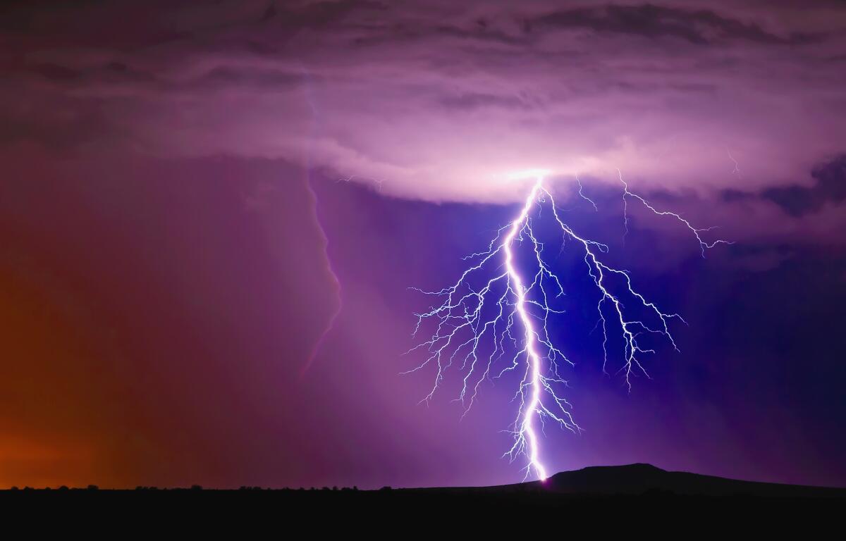 A large lightning bolt strikes in a purple cloudy sky.