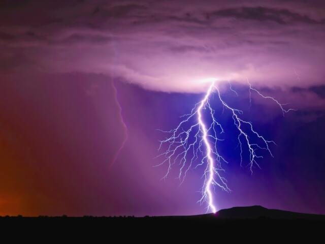 A large lightning bolt strikes in a purple cloudy sky.