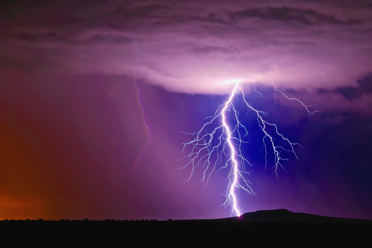 A large lightning bolt strikes in a purple cloudy sky.