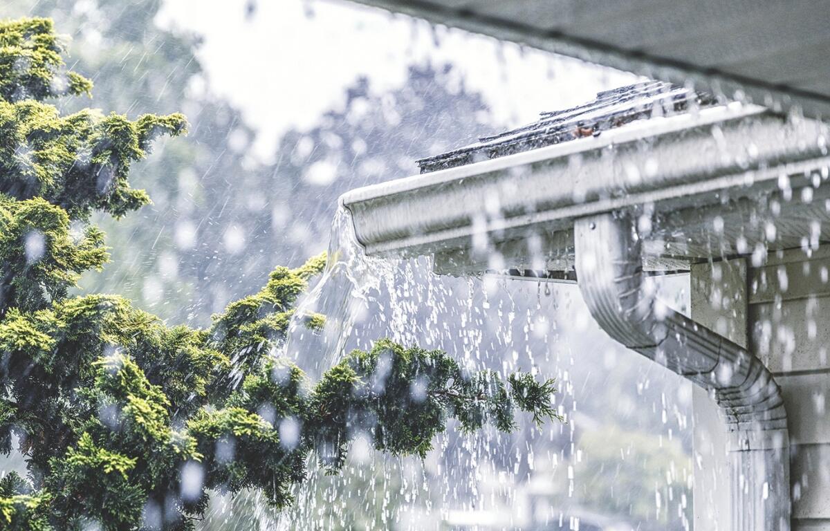 Heavy rain pours out of a gutter on a house