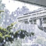 Heavy rain pours out of a gutter on a house