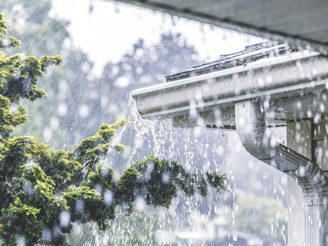 Heavy rain pours out of a gutter on a house