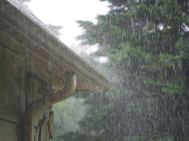 Heavy rain pours out of a gutter on a house