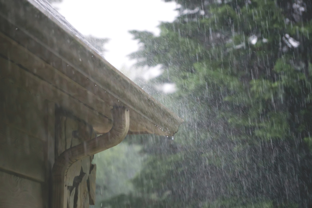 Heavy rain pours out of a gutter on a house