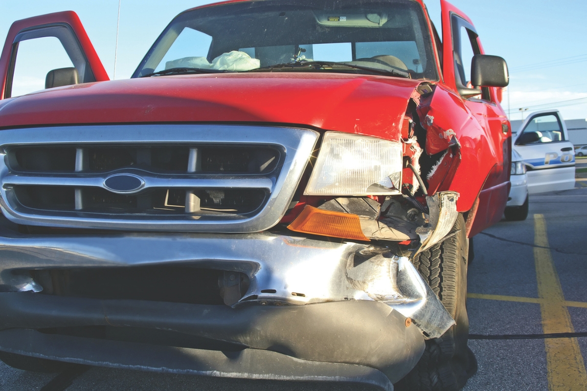 A small red pickup truck with a smashed front fender and light.