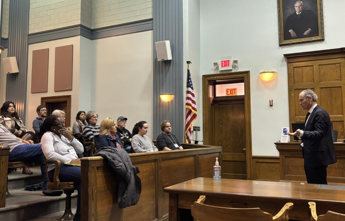 Members of the Harrisonburg community sit in council chambers while observing a speaker.