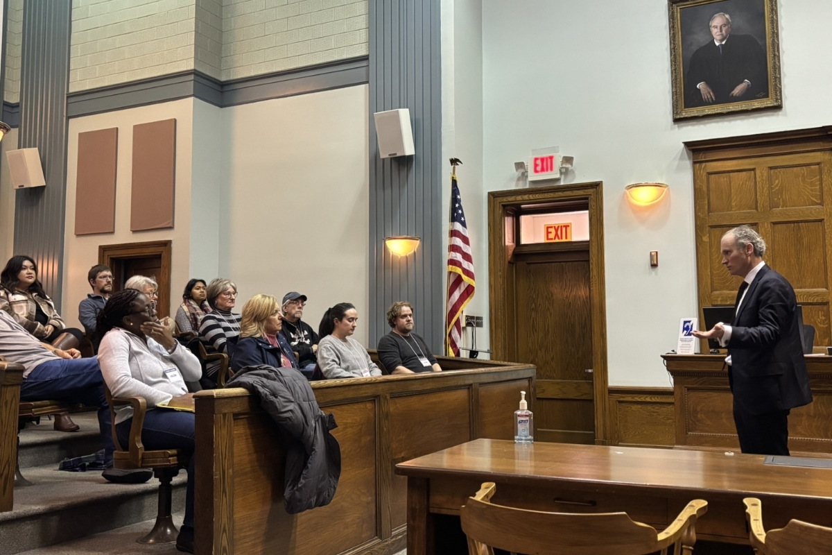 Members of the Harrisonburg community sit in council chambers while observing a speaker.