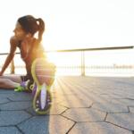 A young woman sitting on the ground stretching.