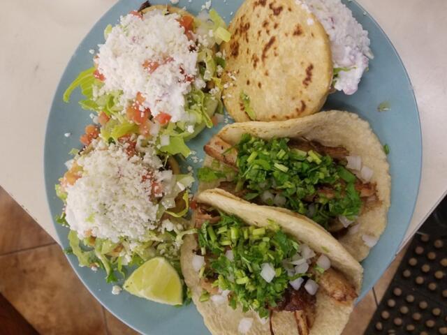 A plate full of tacos pupusas and salad.