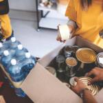 Workers packing a box with canned goods.